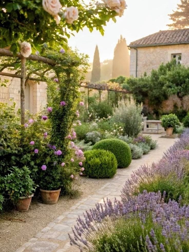 Lush garden with stone path, purple lavender, rounded shrubs, and climbing roses.