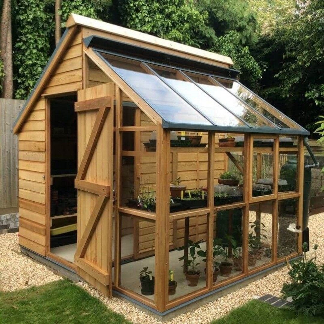Wooden garden shed and greenhouse hybrid with glass panels and potted plants inside.