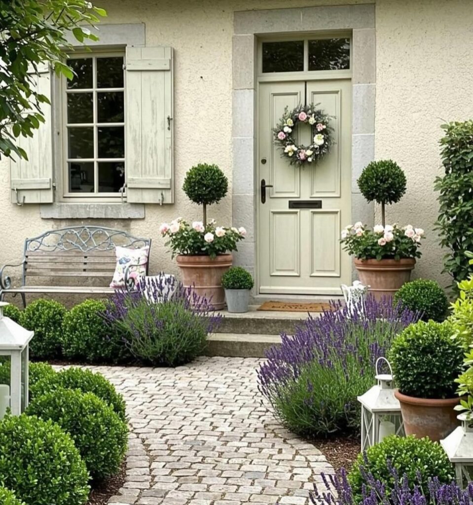 Cobblestone patterned pavers walkway lined with purple lavender and manicured green shrubs.