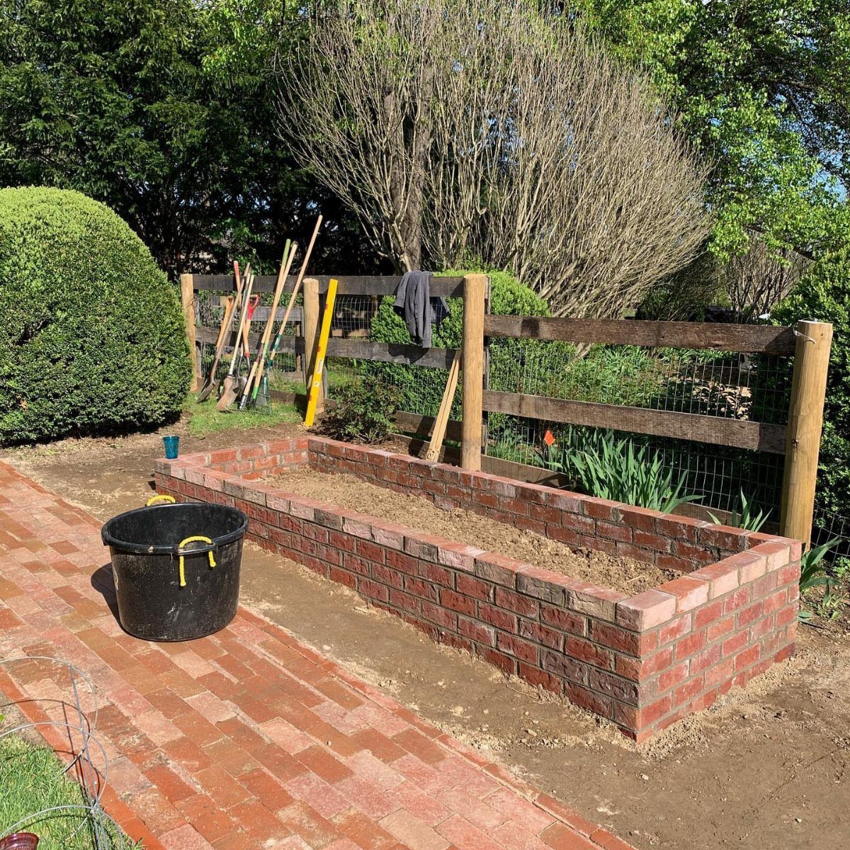 Rectangular red brick raised garden bed with a brick cap and nearby path.