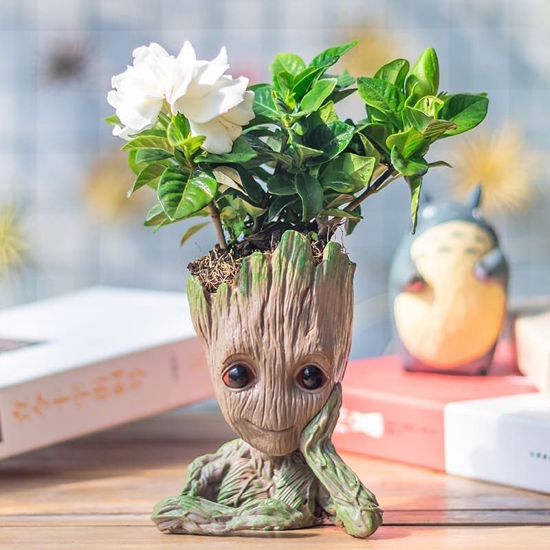 Groot man planter with a thinking pose holding a green plant with white flowers